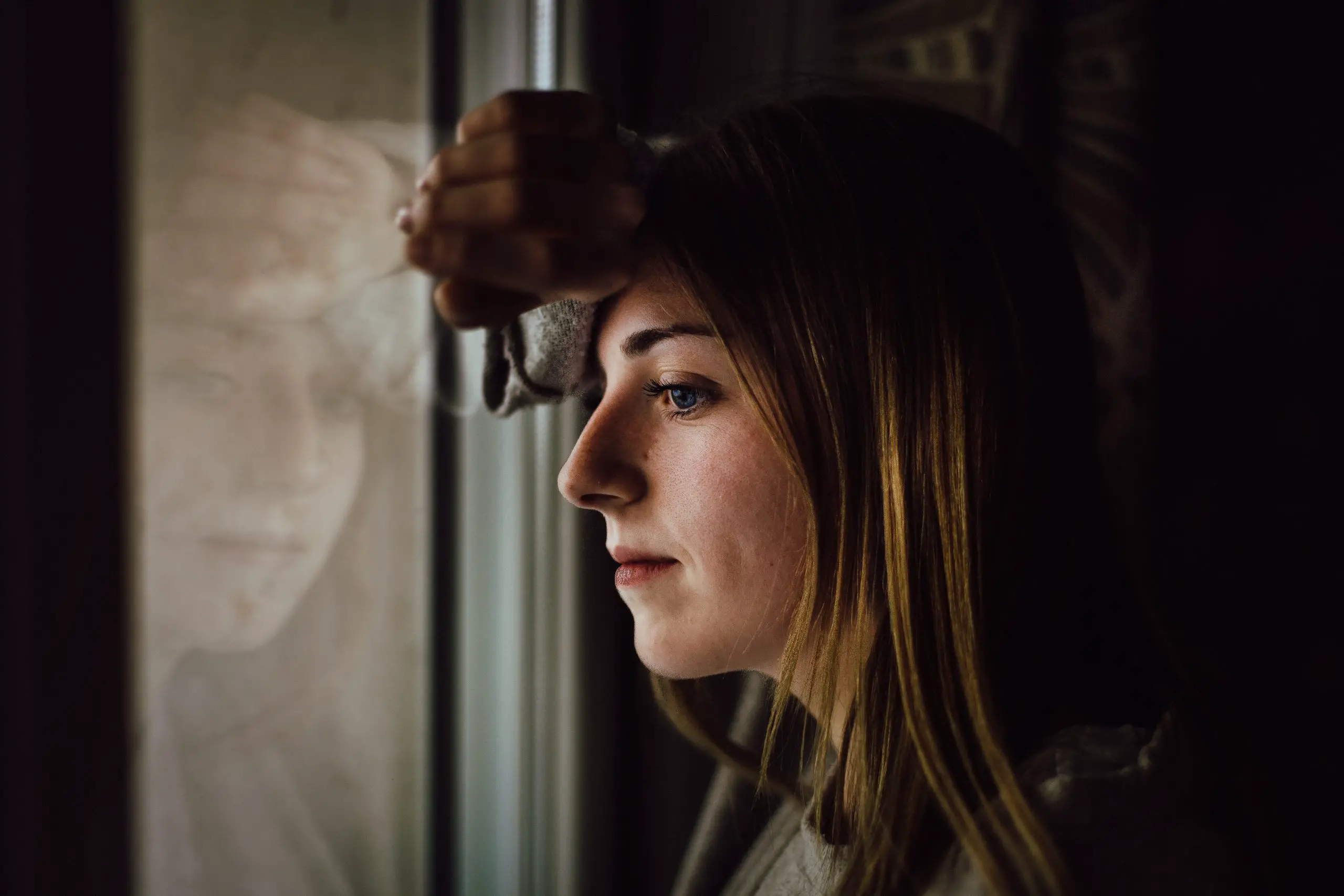 Young sad woman staring out of window